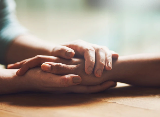 pair of hands clasping another's hand in compassionate care